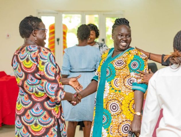 Two women shake hands whilst laughing and smiling