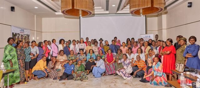 A large group of women are gathered in a large room for a group photo